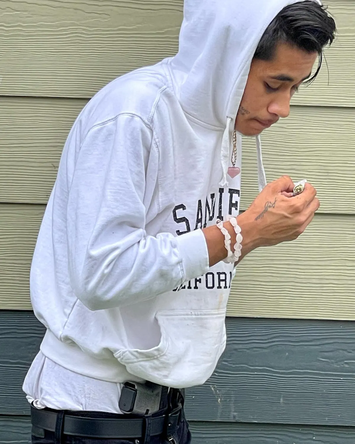 John Caicedo in a white hooded sweatshirt against green siding