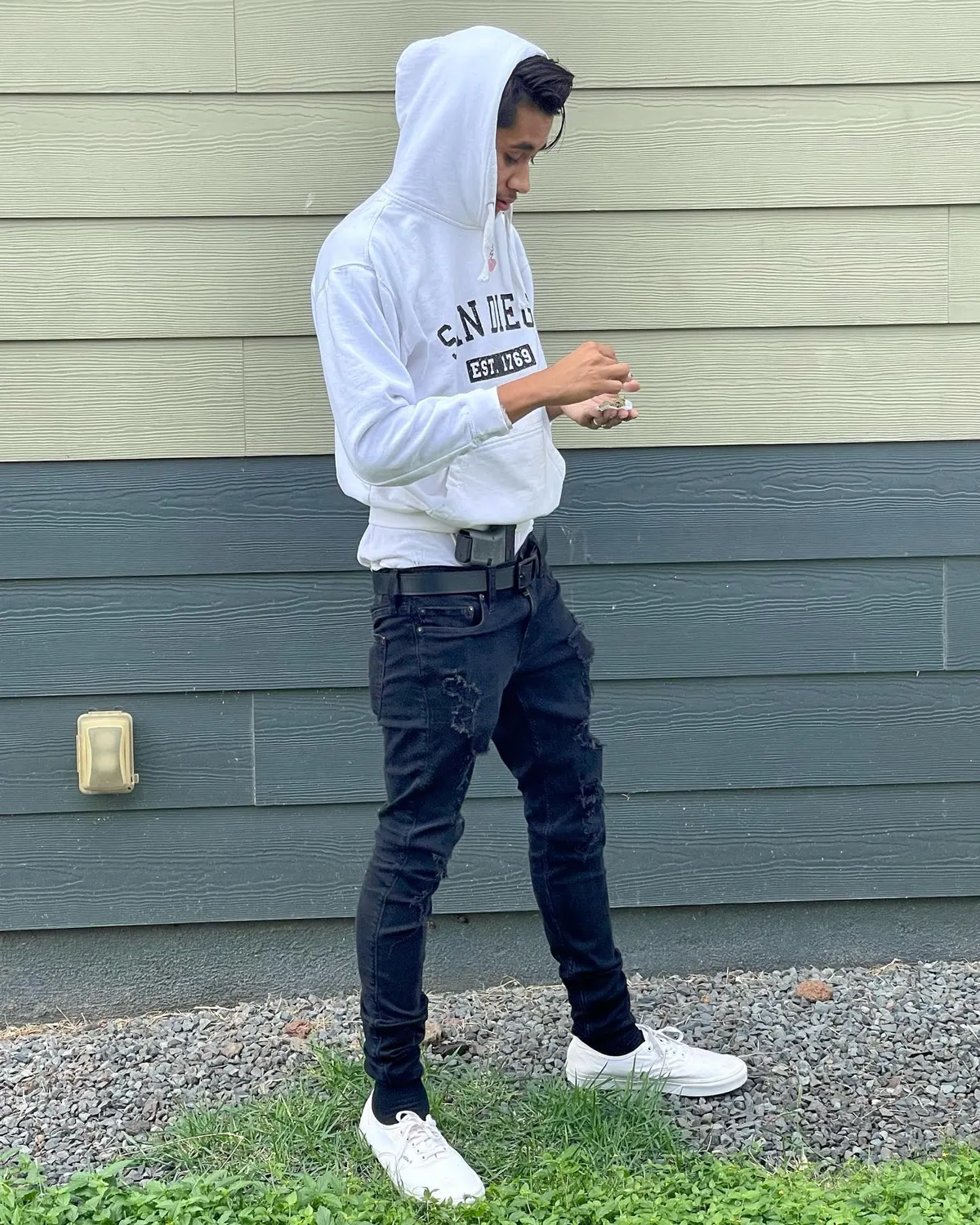 John Caicedo standing in a white hoodie and black jeans