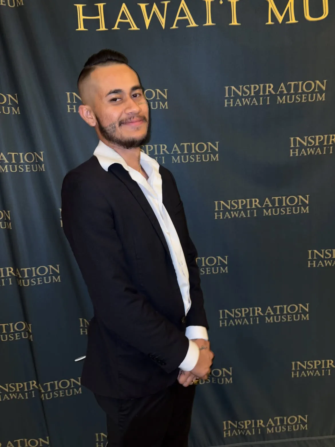 John Caicedo in a black suit at a museum event backdrop