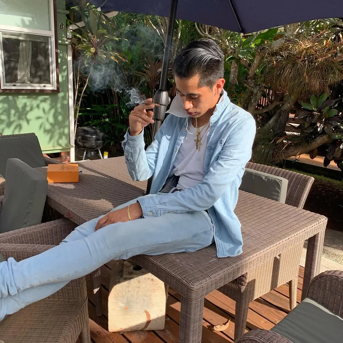 John Caicedo in a light denim jacket seated on a garden patio