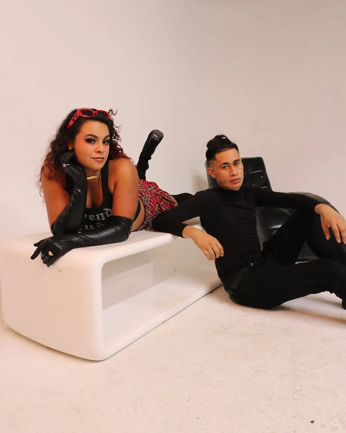 John Caicedo and a collaborator posed on a white bench in a studio